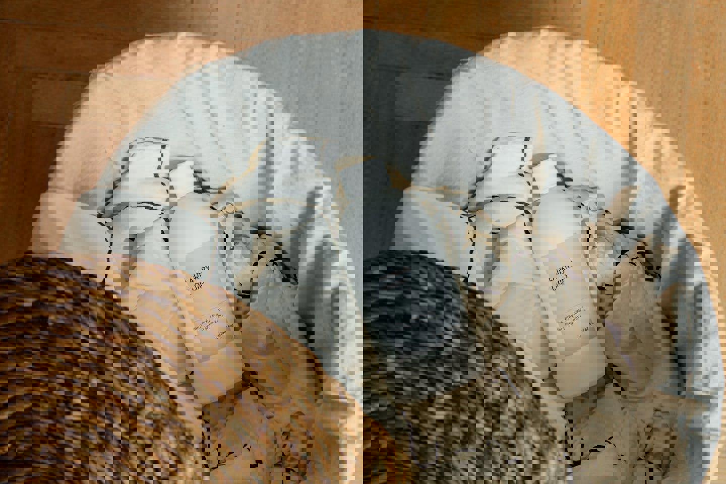 a bottle of laundry liquid sits in a laundry basket