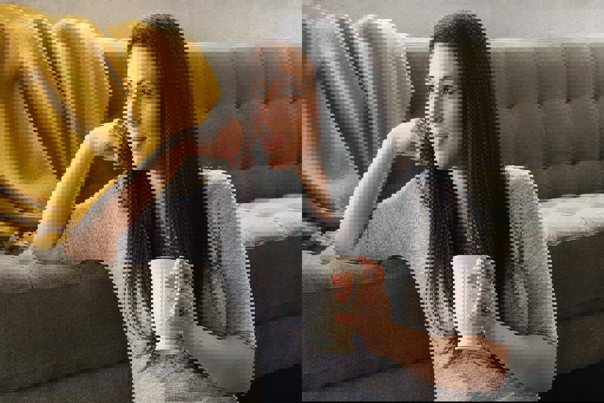 a woman sitting on a couch holding a cup of coffee