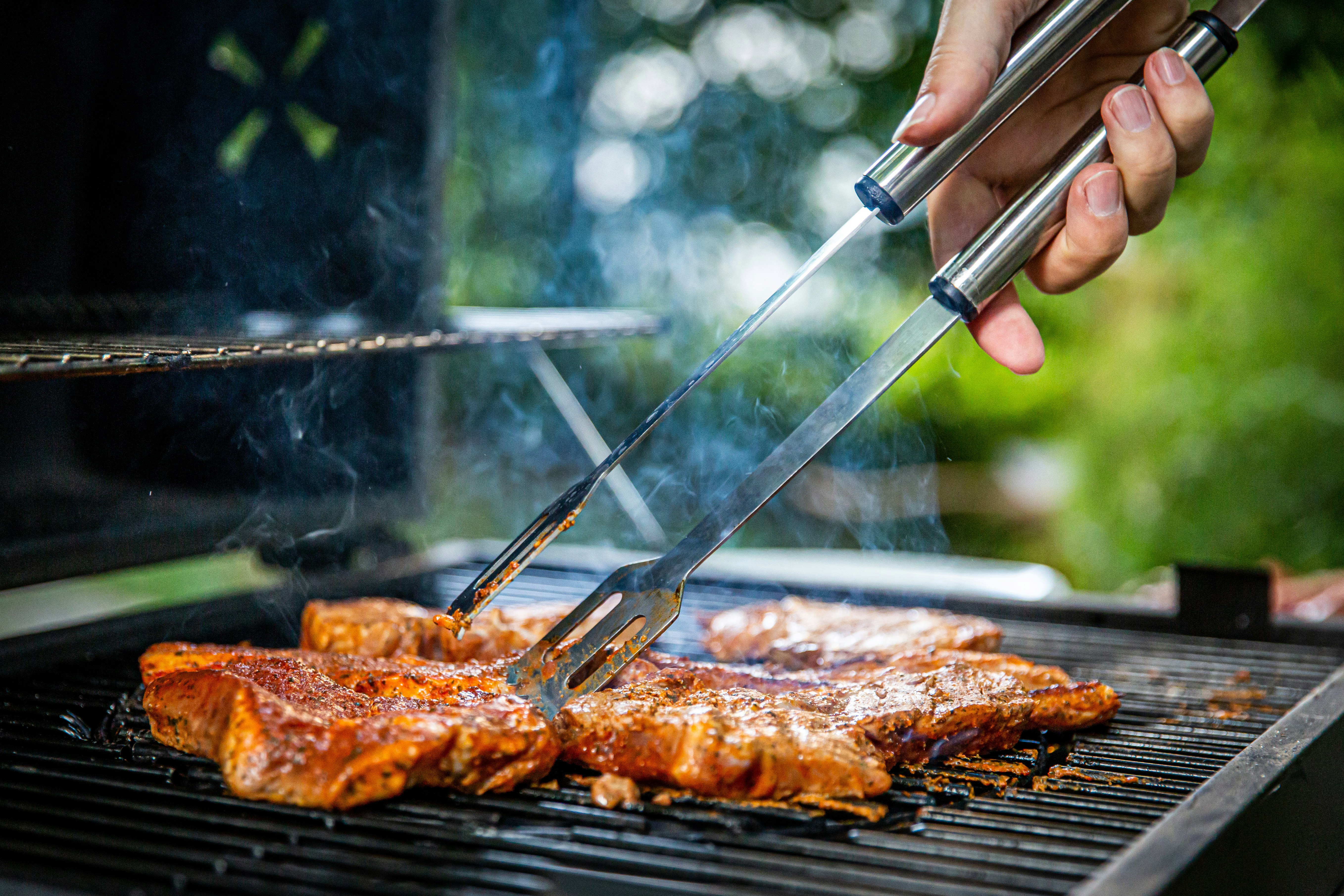 a person is grilling meat on a grill with tongs