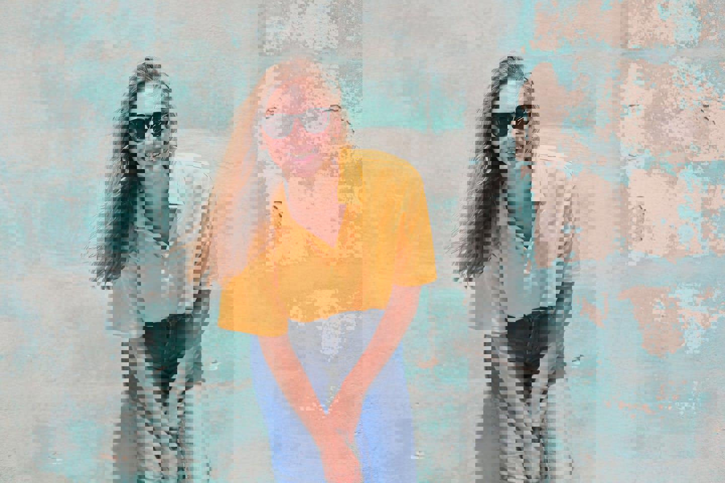 a woman wearing sunglasses and a yellow shirt is sitting in front of a blue wall