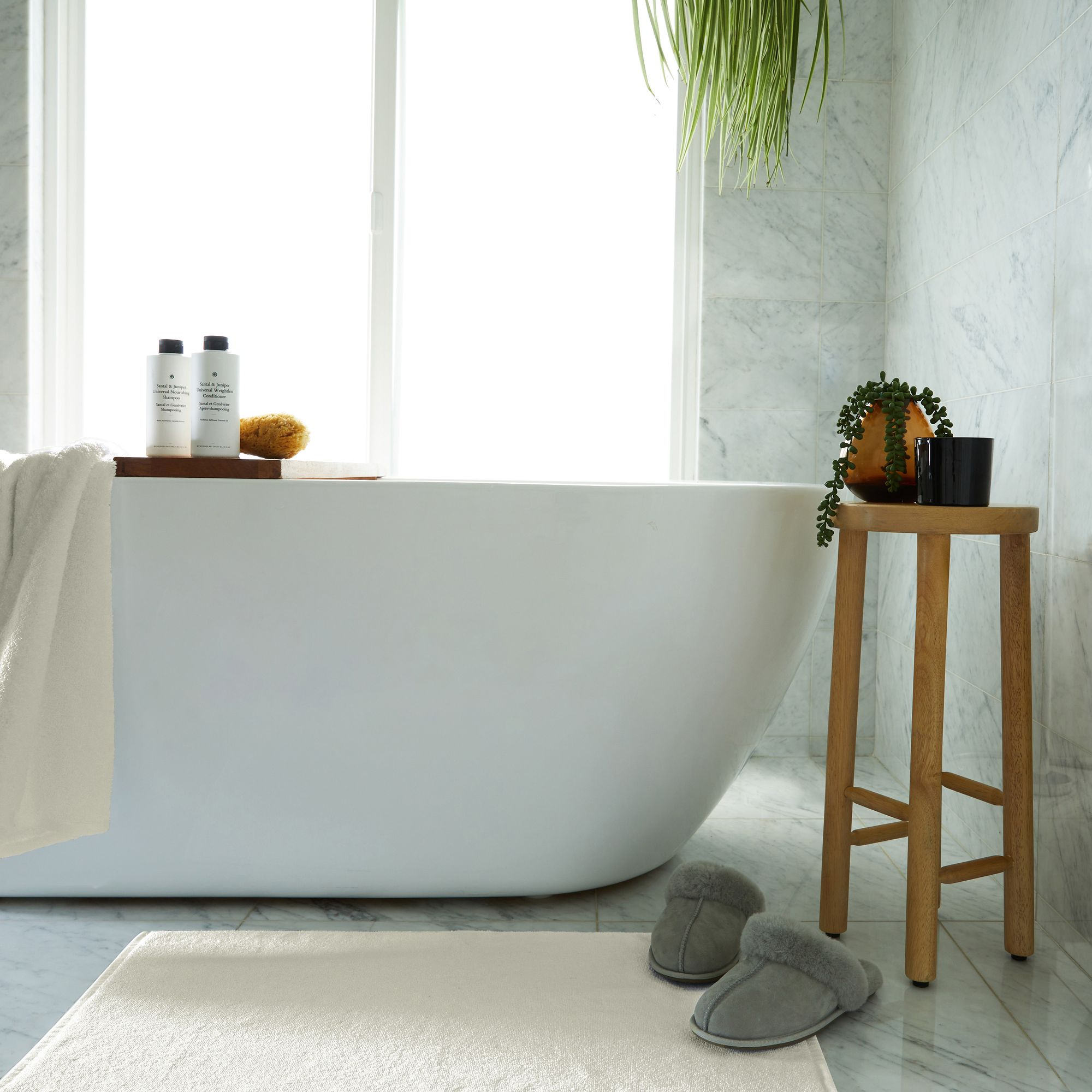 a bathroom with a bathtub , slippers and a wooden stool