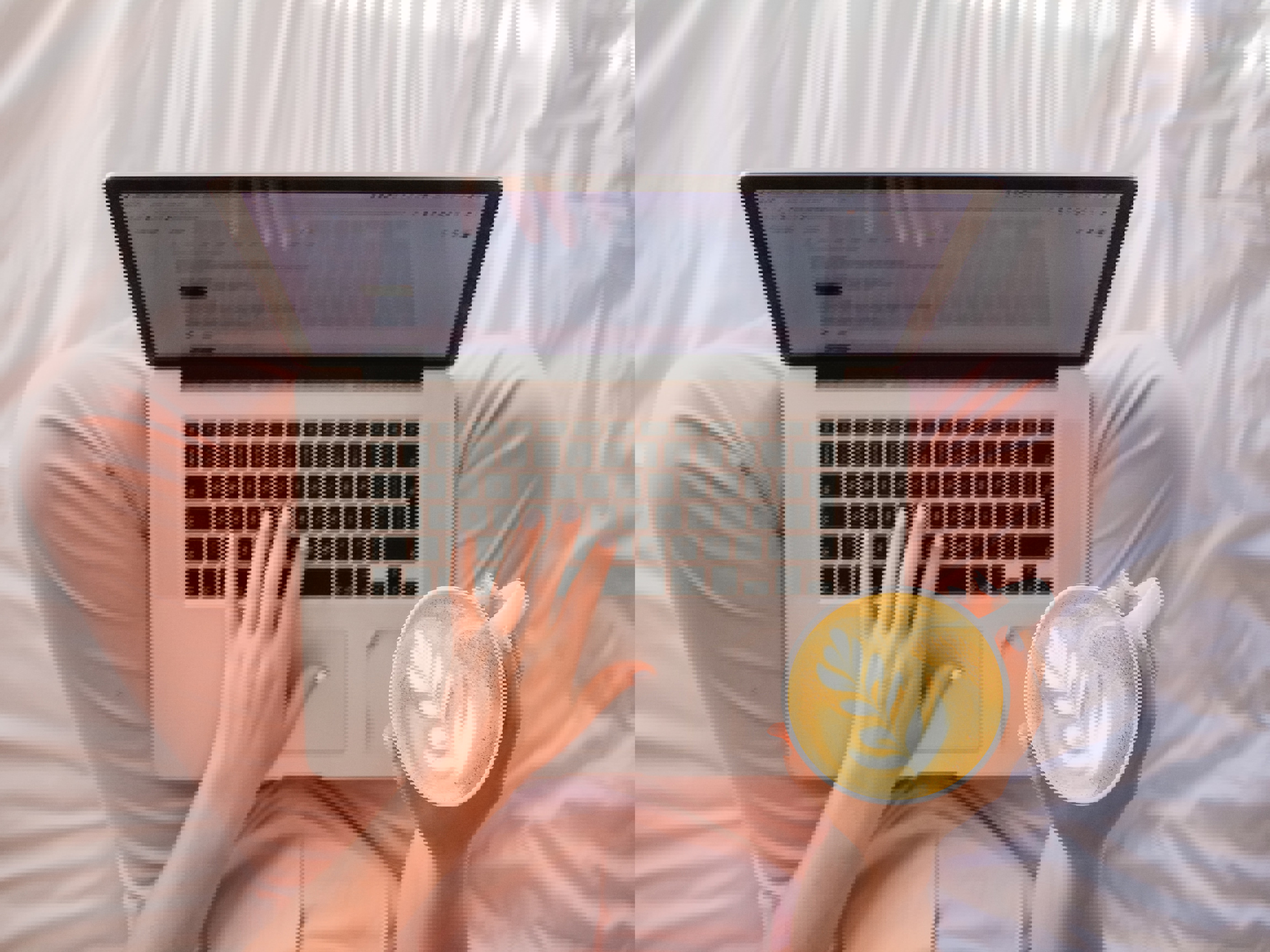 a woman is typing on a laptop while holding a cup of coffee