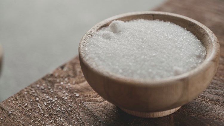 a wooden bowl filled with white sugar on a table