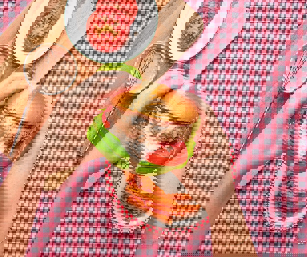 a person is holding a hamburger with lettuce and tomatoes