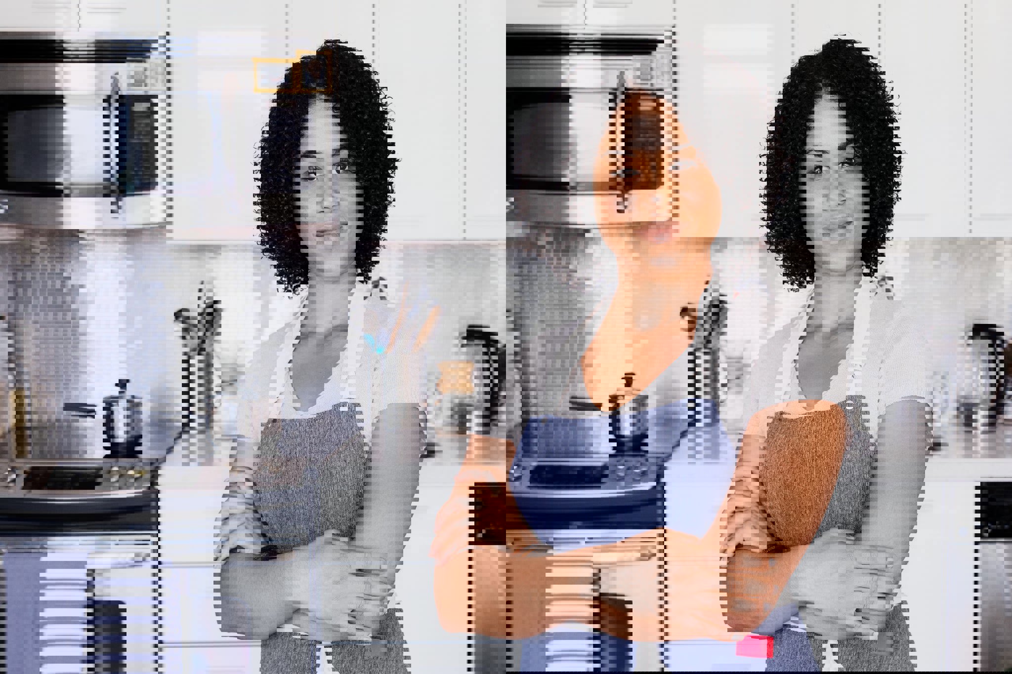 a woman in an apron stands in a kitchen with her arms crossed