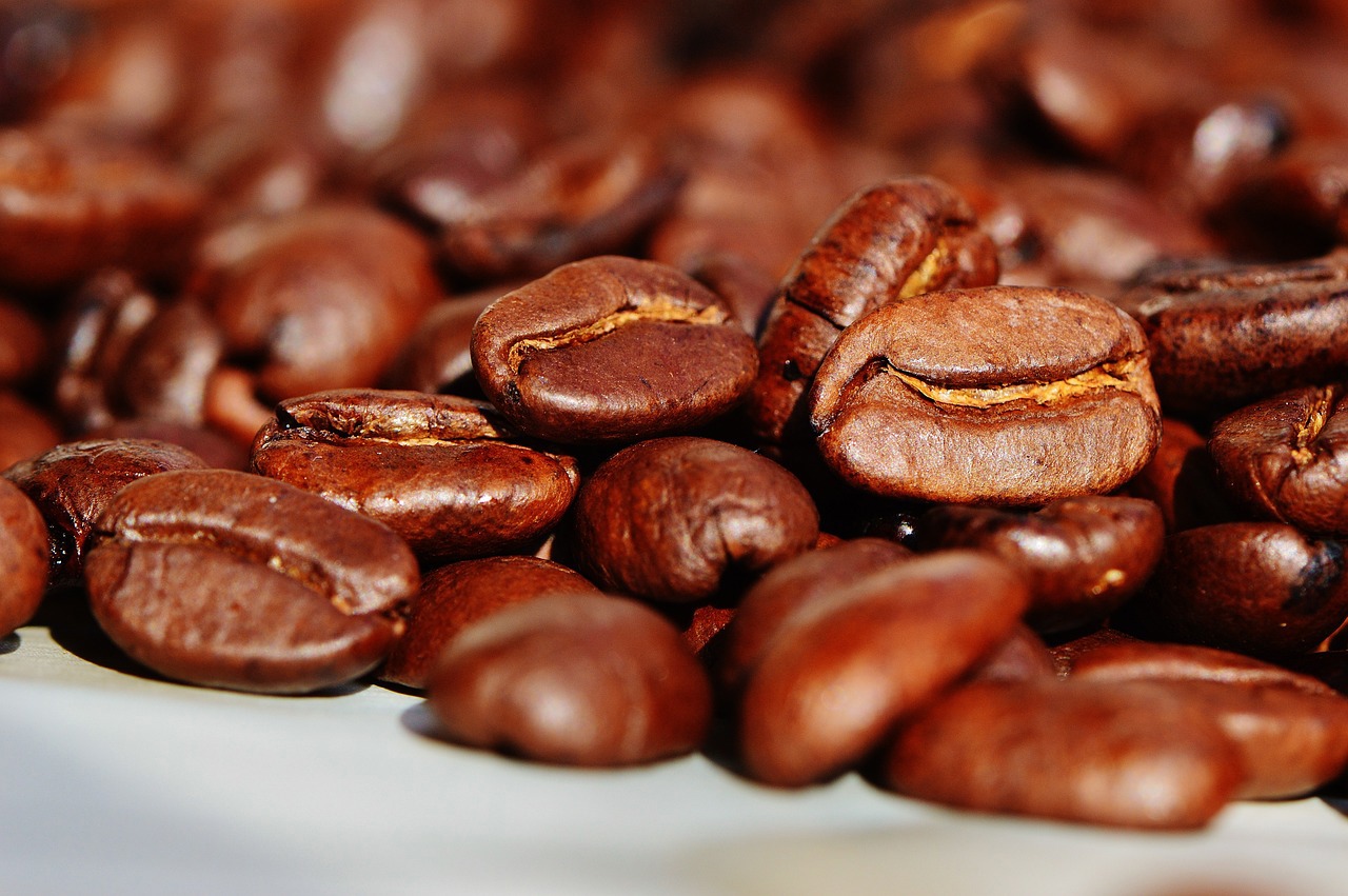 a pile of roasted coffee beans on a white surface