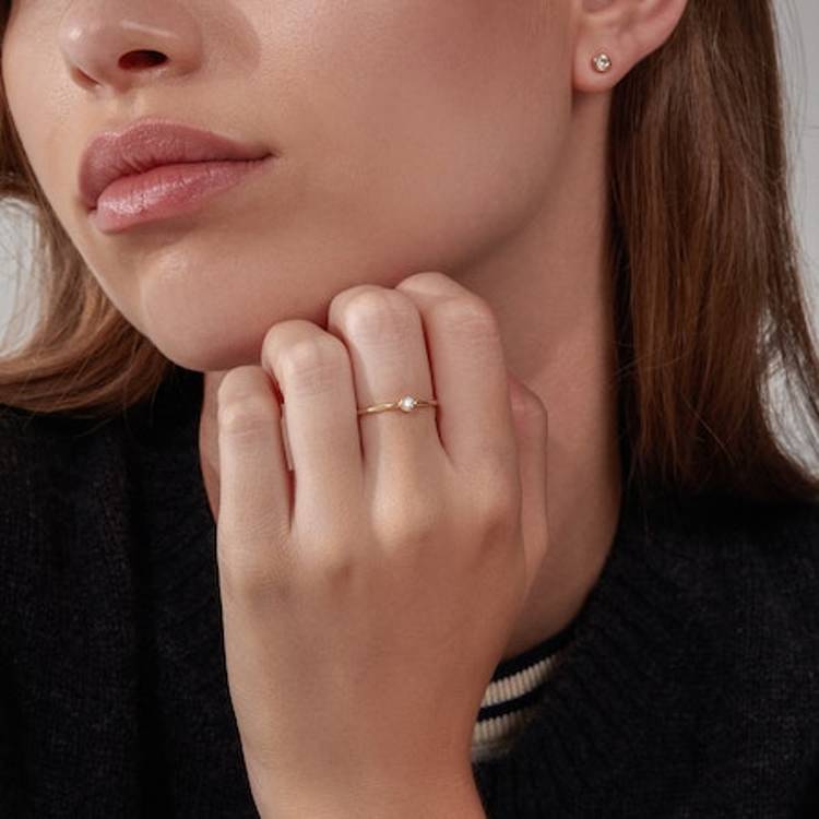 a woman is wearing a ring and earrings on her left hand