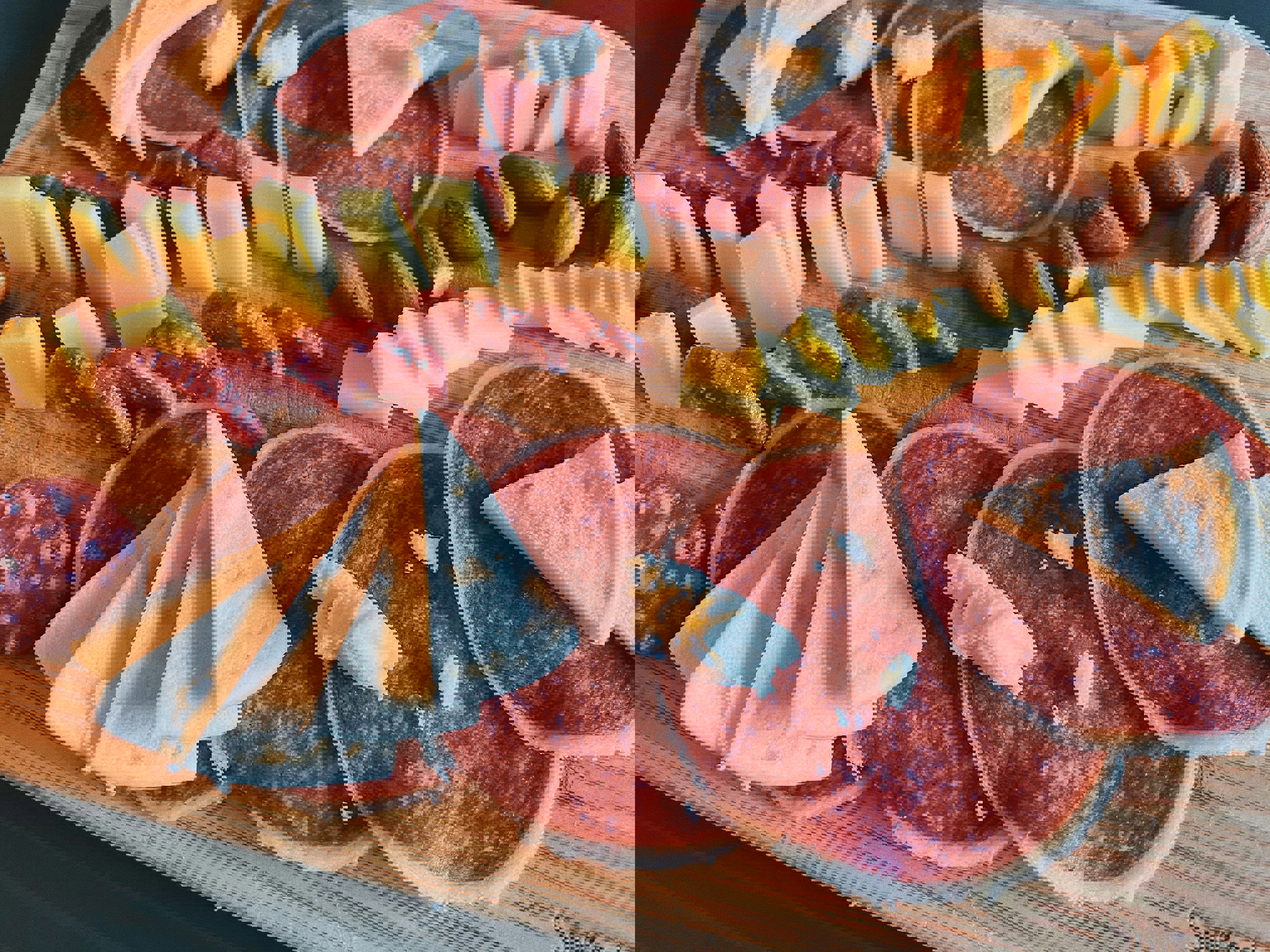 a wooden cutting board with slices of salami cheese and nuts