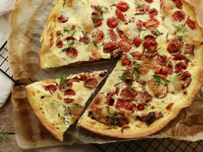 a pizza with tomatoes and cheese has a slice taken out of it