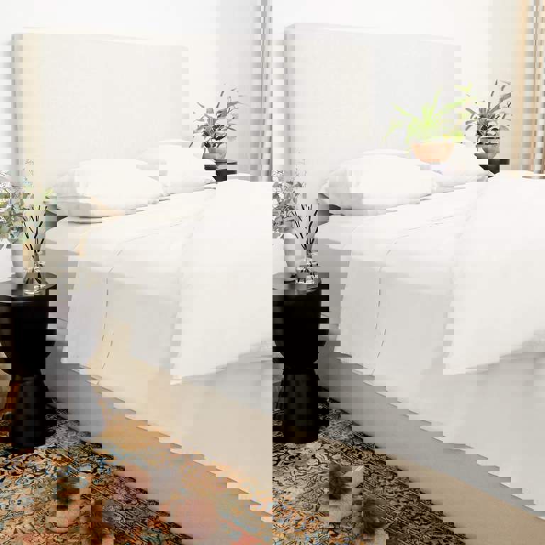 a bed with white sheets and pillows in a bedroom