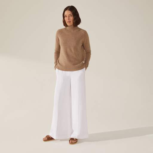 a woman wearing a tan sweater and white pants