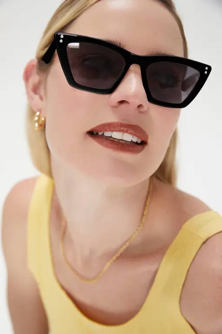 a close up of a woman wearing sunglasses and a yellow tank top