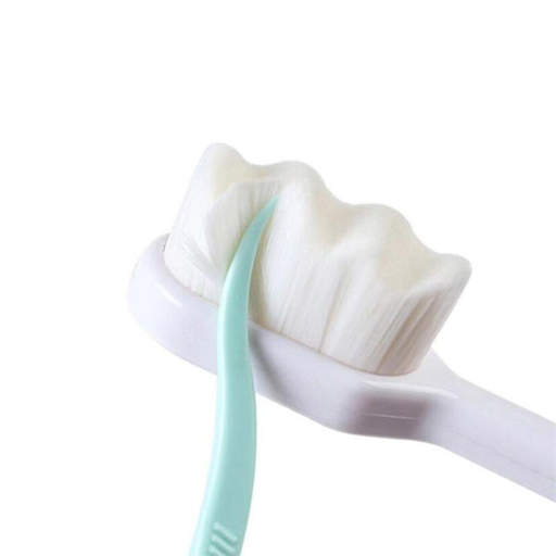 a close up of a white toothbrush with a green handle