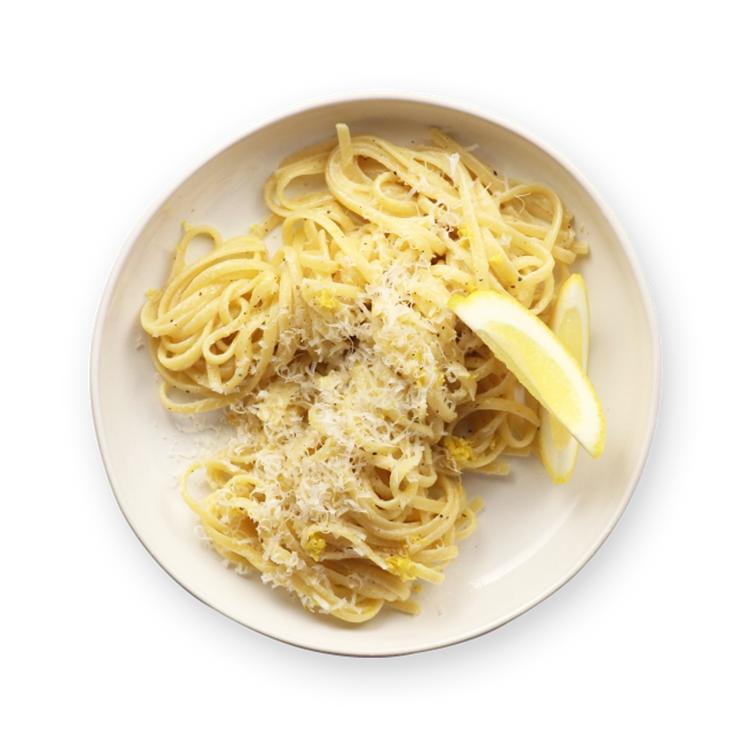 a white plate topped with noodles and a slice of lemon