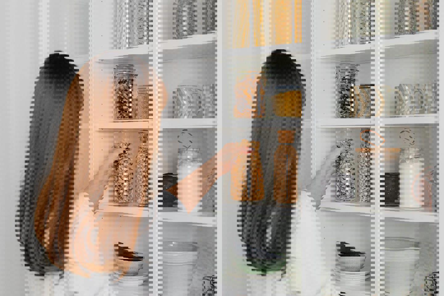 a woman is taking a jar of granola out of a pantry