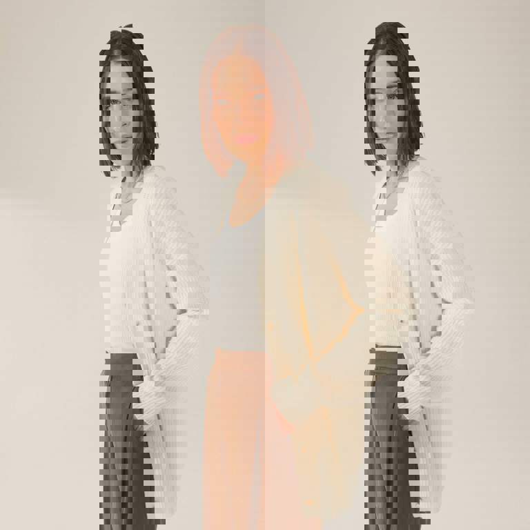 a woman wearing a white cardigan and brown pants