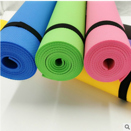 four different colored yoga mats are rolled up on a white surface