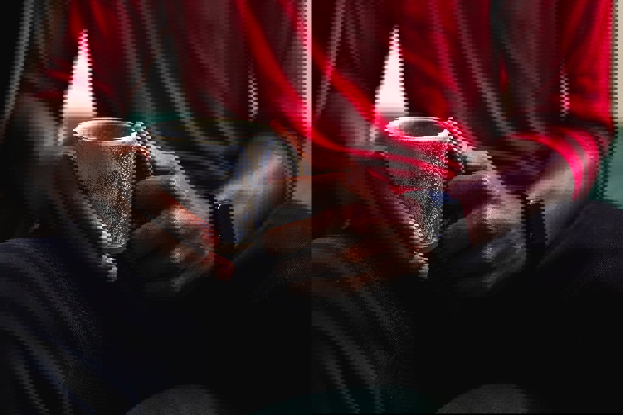 a man in a red shirt is holding a cup of coffee