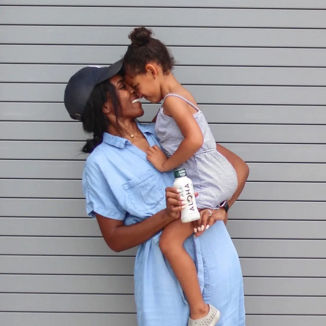 a woman is holding a little girl in her arms while holding a bottle of water