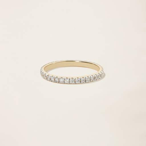a yellow gold ring with diamonds on a white background