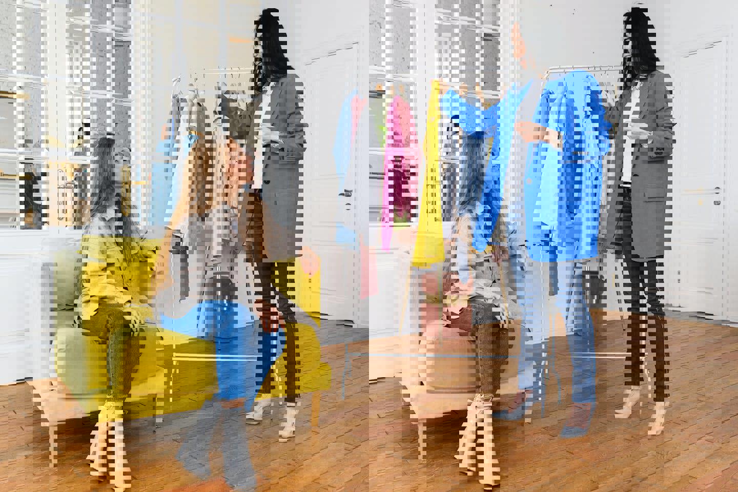 a woman in a blue coat is standing next to a woman in a yellow chair