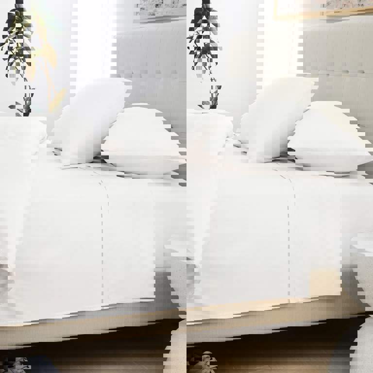 a bed with white sheets and pillows in a bedroom