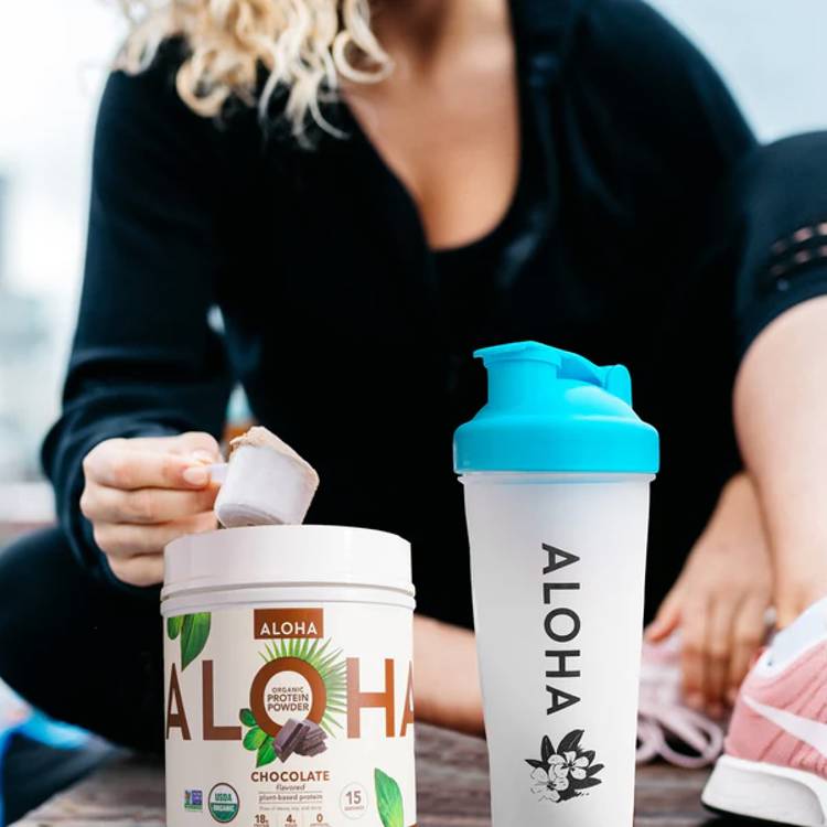 a woman is taking a scoop of chocolate protein powder out of a can next to a shaker