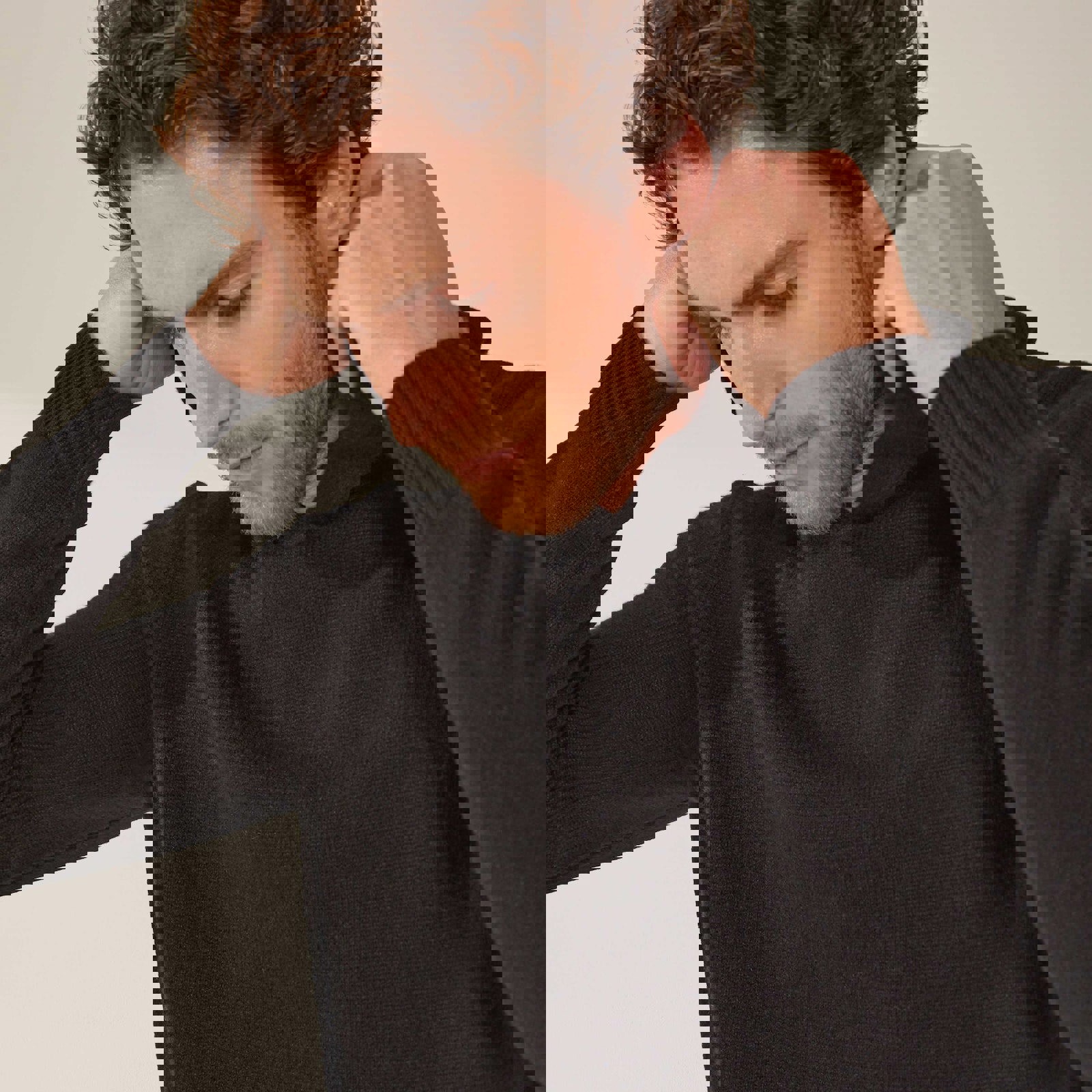 a man with a beard is wearing a black sweater with a hood