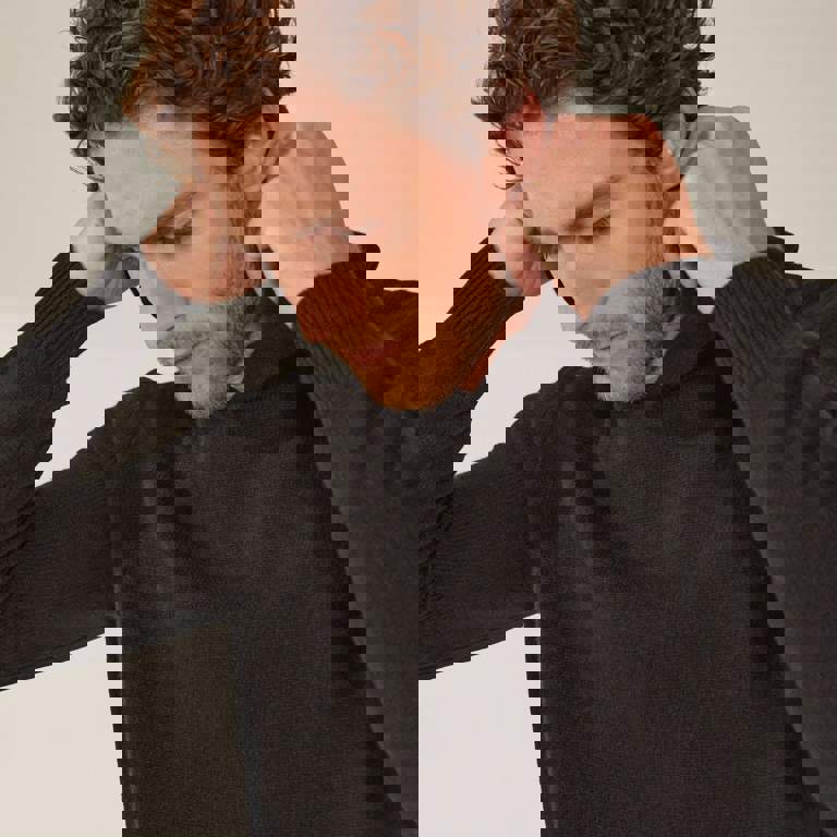 a man with a beard is wearing a black sweater with a hood