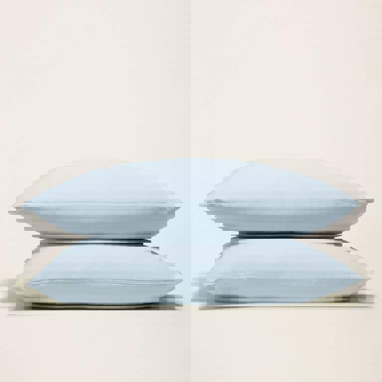 two light blue pillows are stacked on top of each other