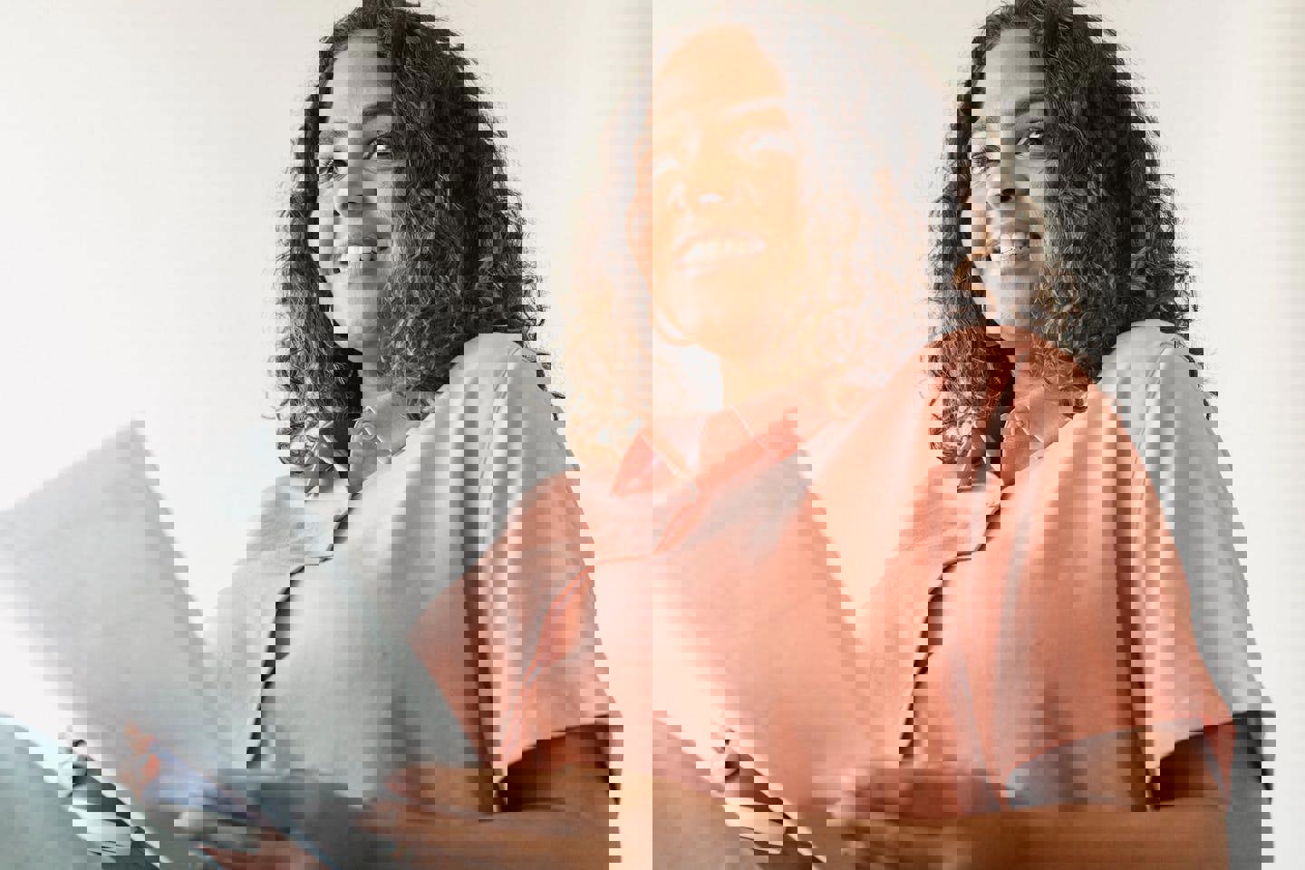 a woman in a pink shirt is holding a piece of paper and smiling