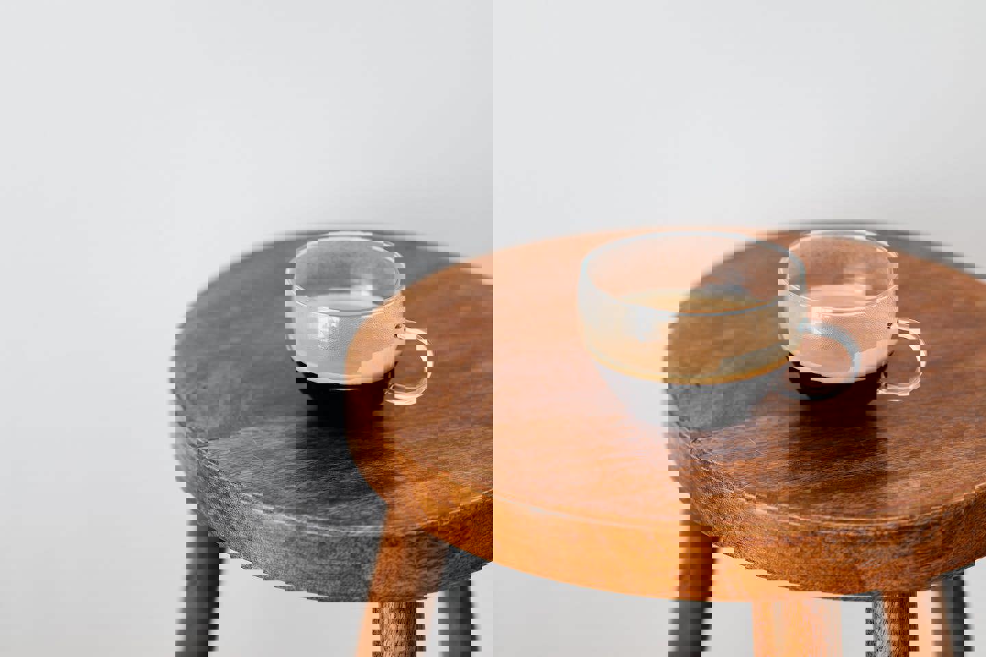 a cup of coffee is sitting on a wooden stool