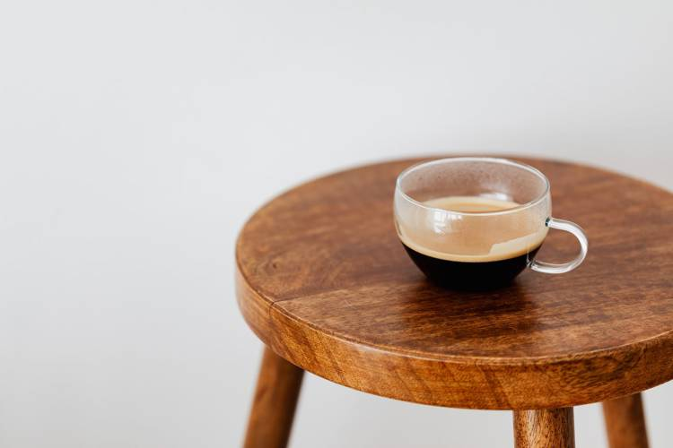 a cup of coffee is sitting on a wooden stool