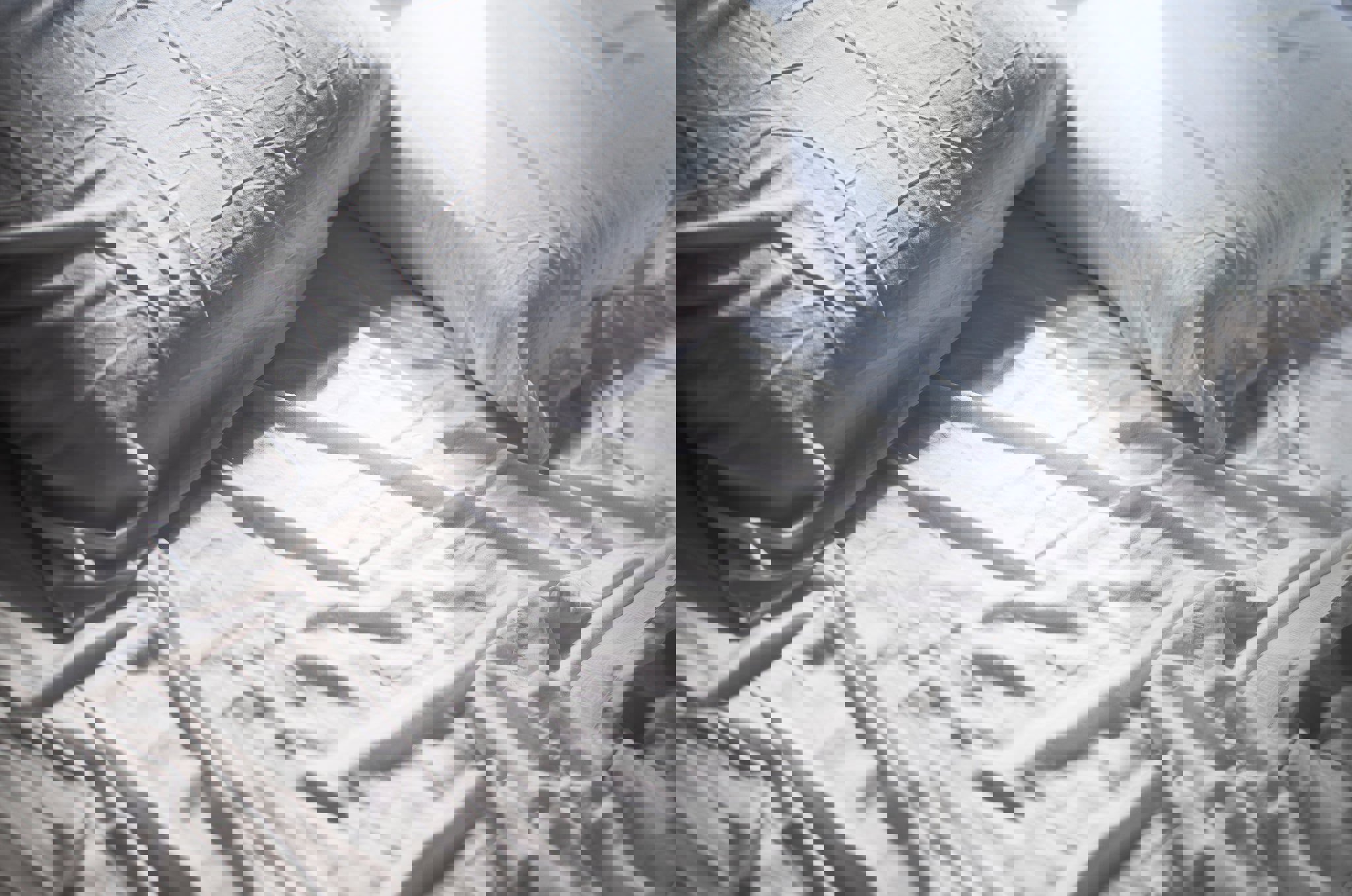 a bed with white sheets and pillows on it