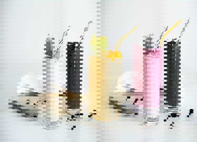 two smoothies in tall glasses with gold straws on a table