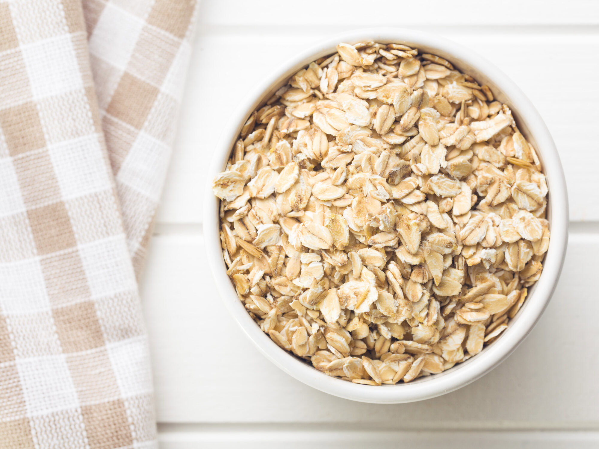 a bowl of oats sits on a table next to a checkered towel