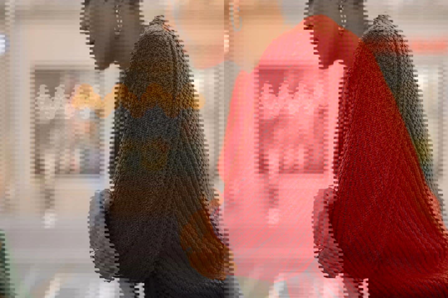 a woman in a red sweater is sitting at a table with her hands folded