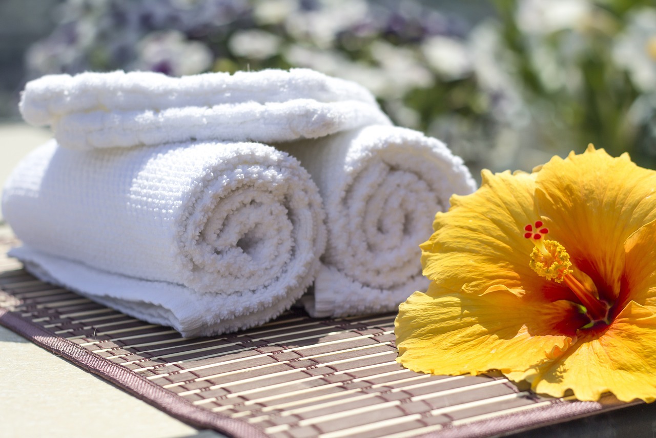 a hibiscus flower sits next to a stack of towels
