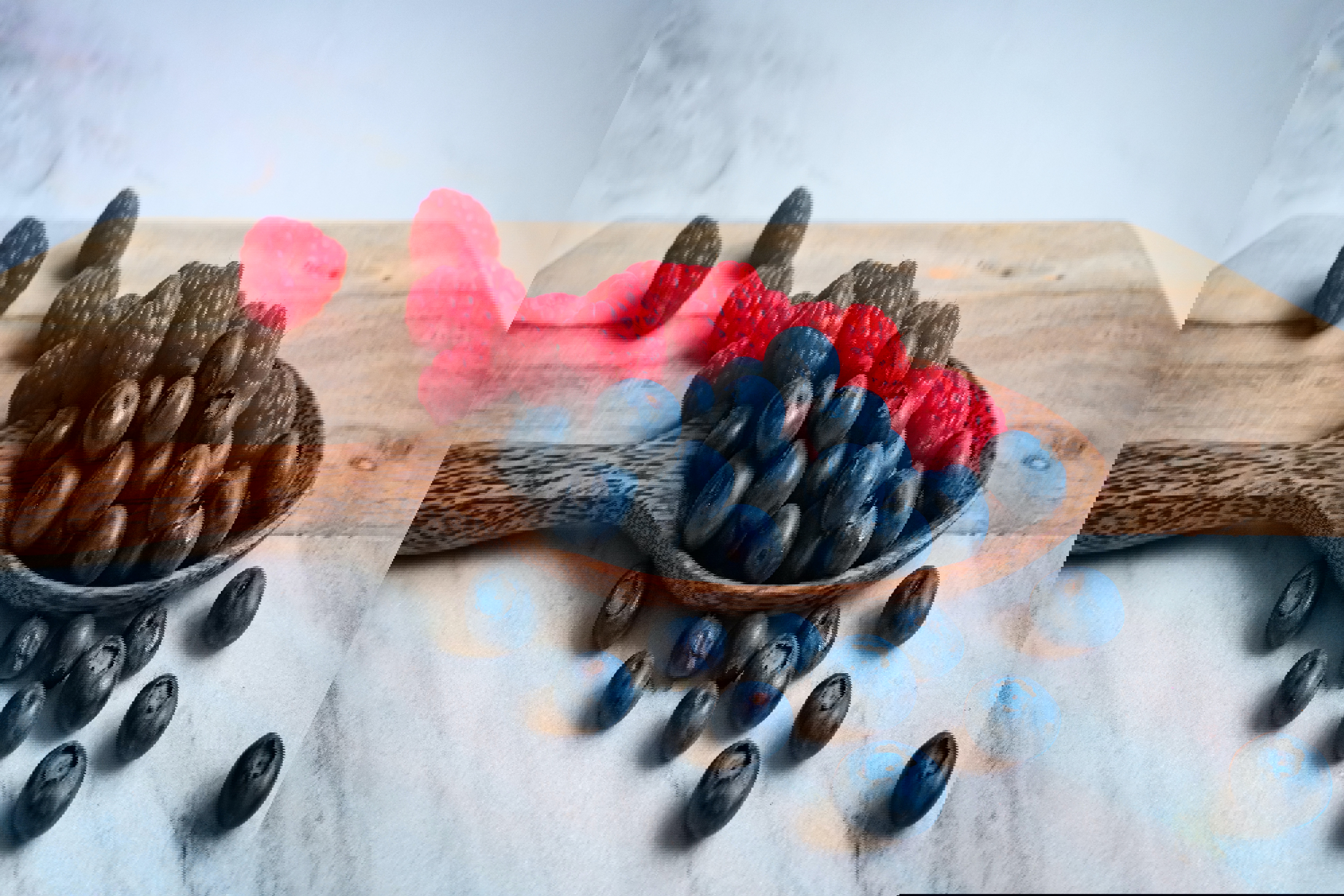 a wooden spoon filled with blueberries and raspberries