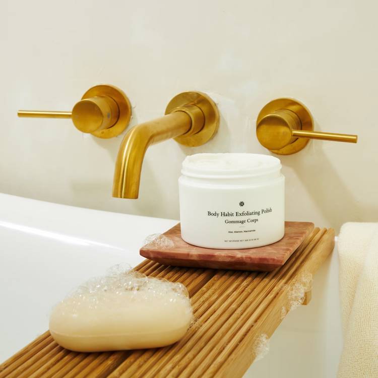 a jar of body habit exfoliating polish sits on a wooden tray next to a bar of soap