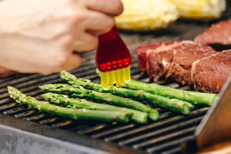 a person is cooking asparagus on a grill
