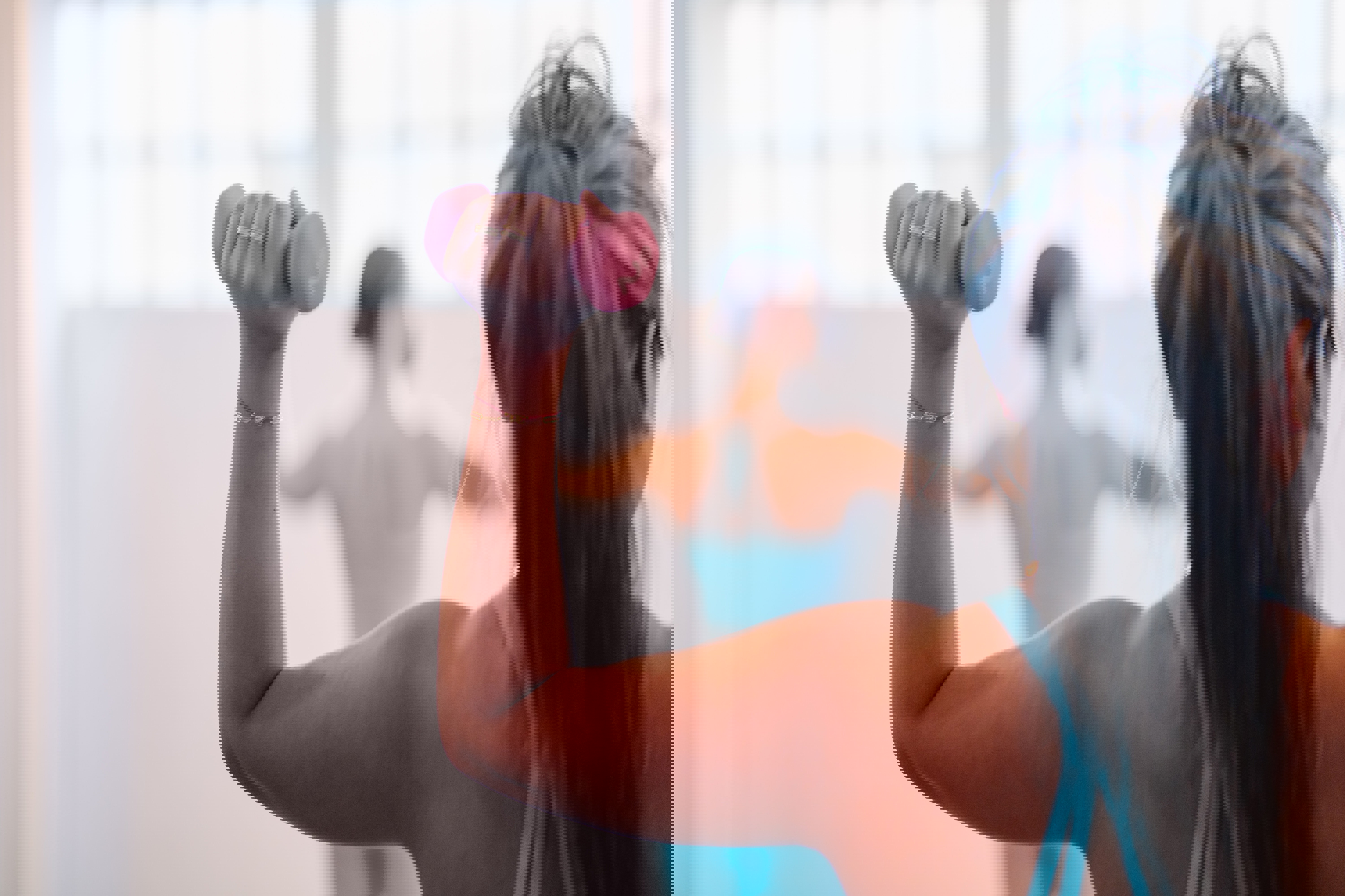 a woman in a blue tank top is lifting a pink dumbbell