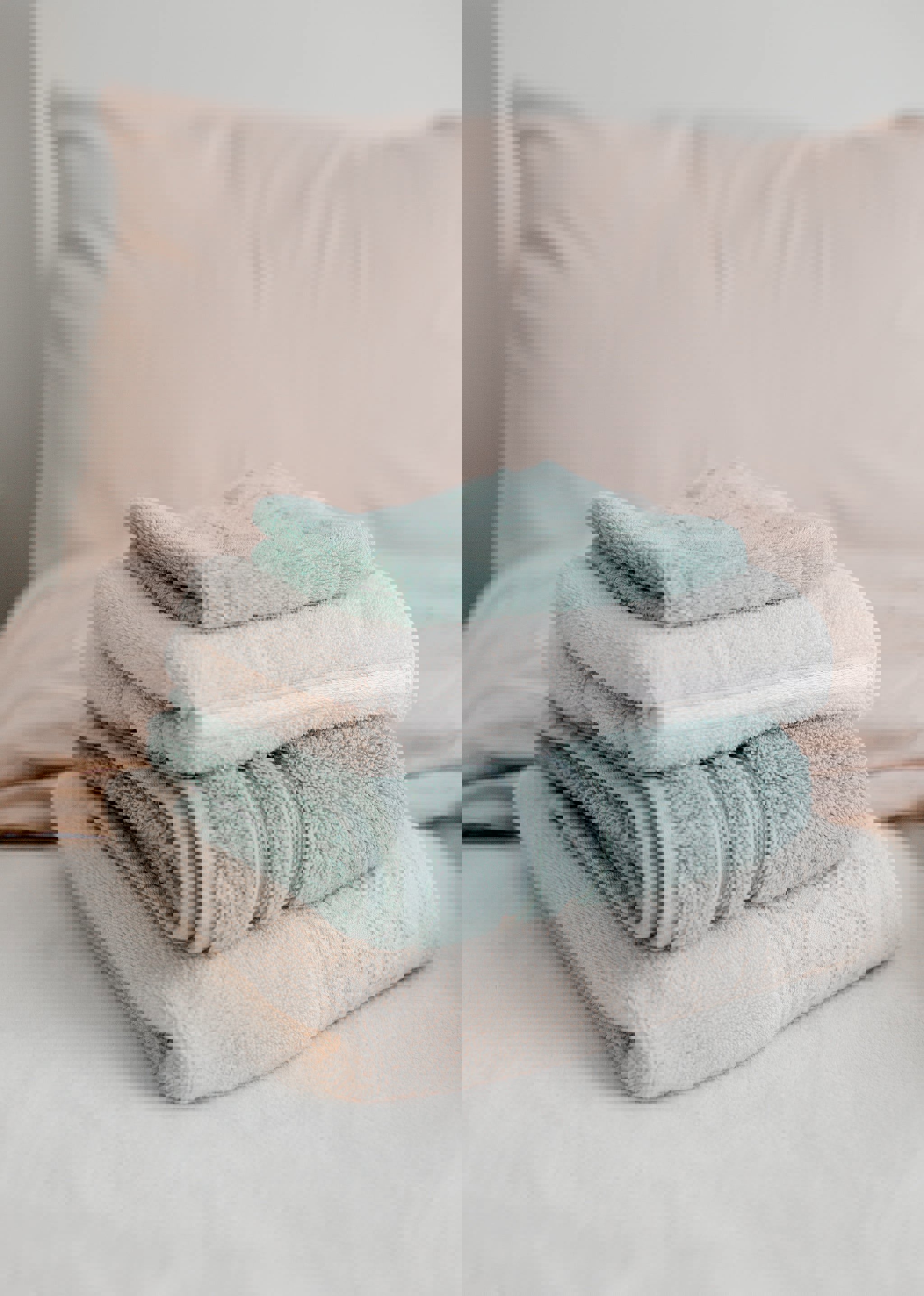 a stack of towels on a bed with a pink pillow