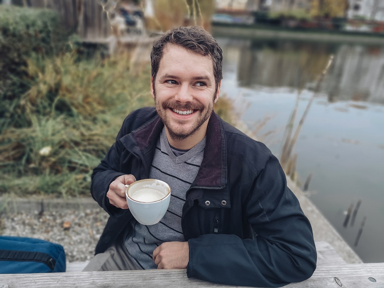 a man in a black jacket is holding a cup of coffee