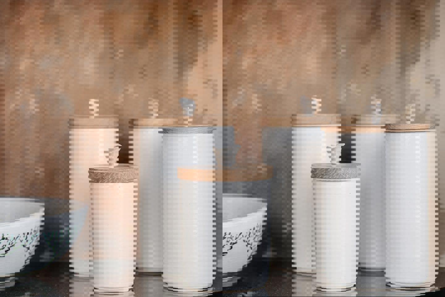 a group of white jars with wooden lids are sitting on a table