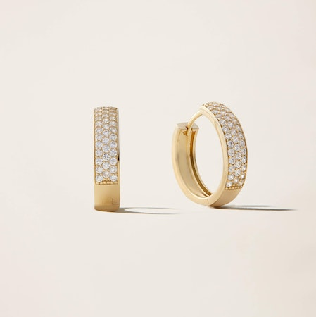 a pair of yellow gold hoop earrings with diamonds on a white surface