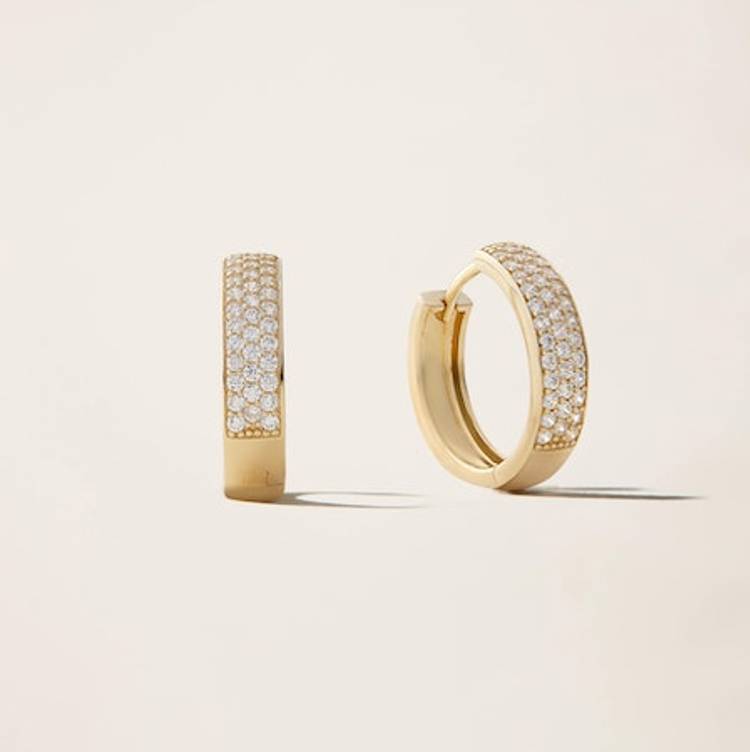 a pair of yellow gold hoop earrings with diamonds on a white surface