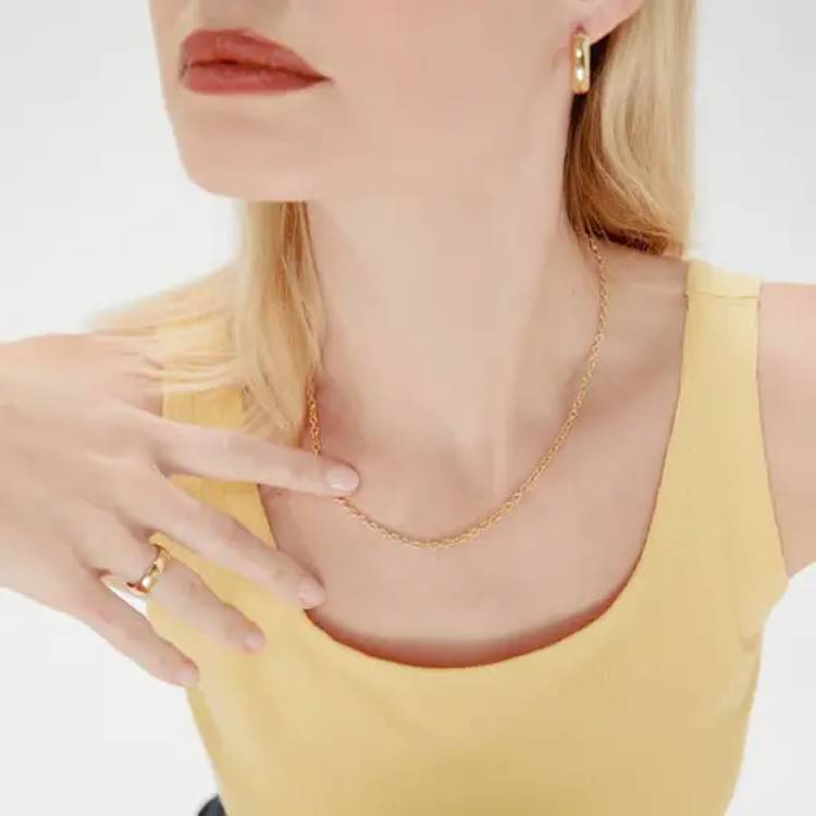 a woman is wearing a gold chain necklace and hoop earrings