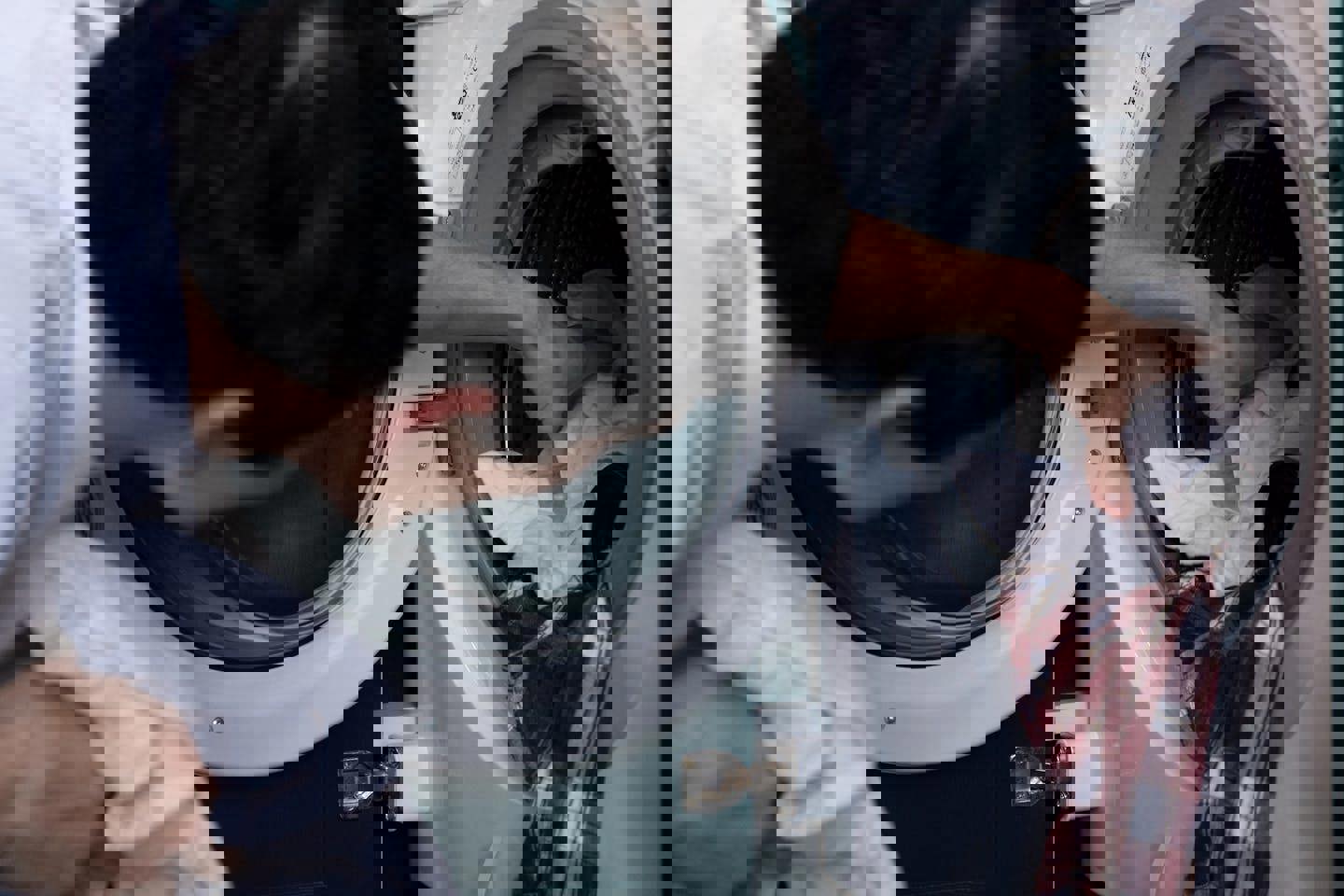 a man is putting clothes in a washing machine