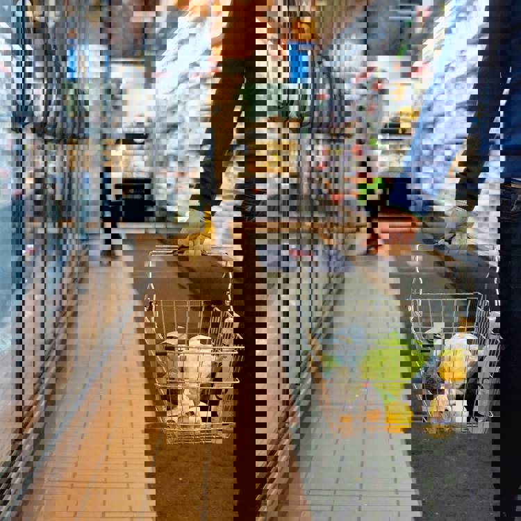 a man is carrying a shopping basket full of groceries in a grocery store